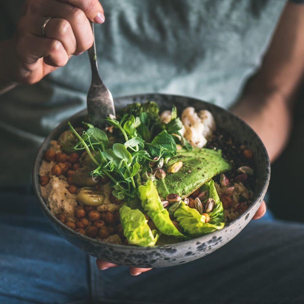 Naturheilpraxis Sabine List 3 Woman eating healthy vegan dish from bowl, square crop